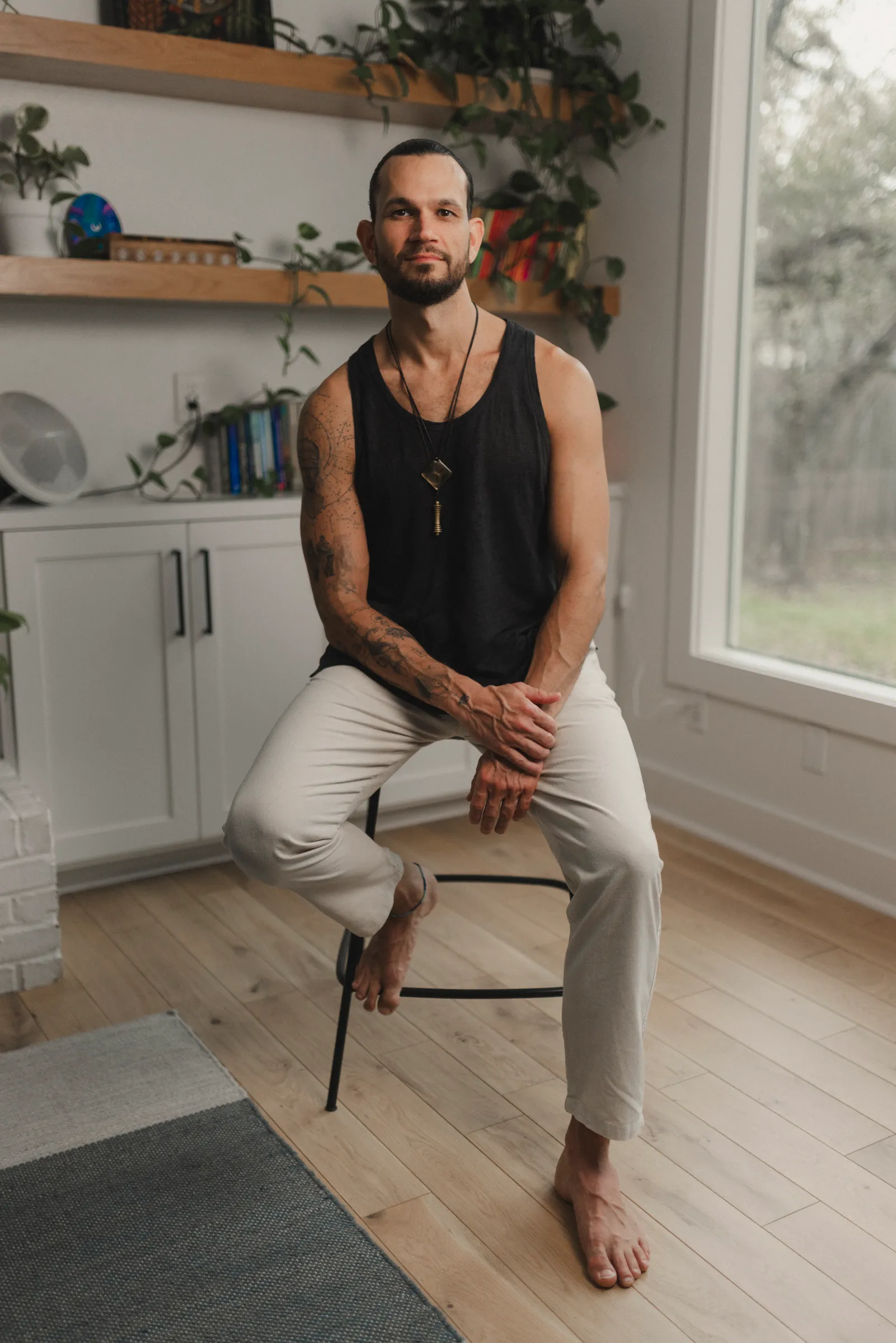 Austin seated at home, barefoot on a stool