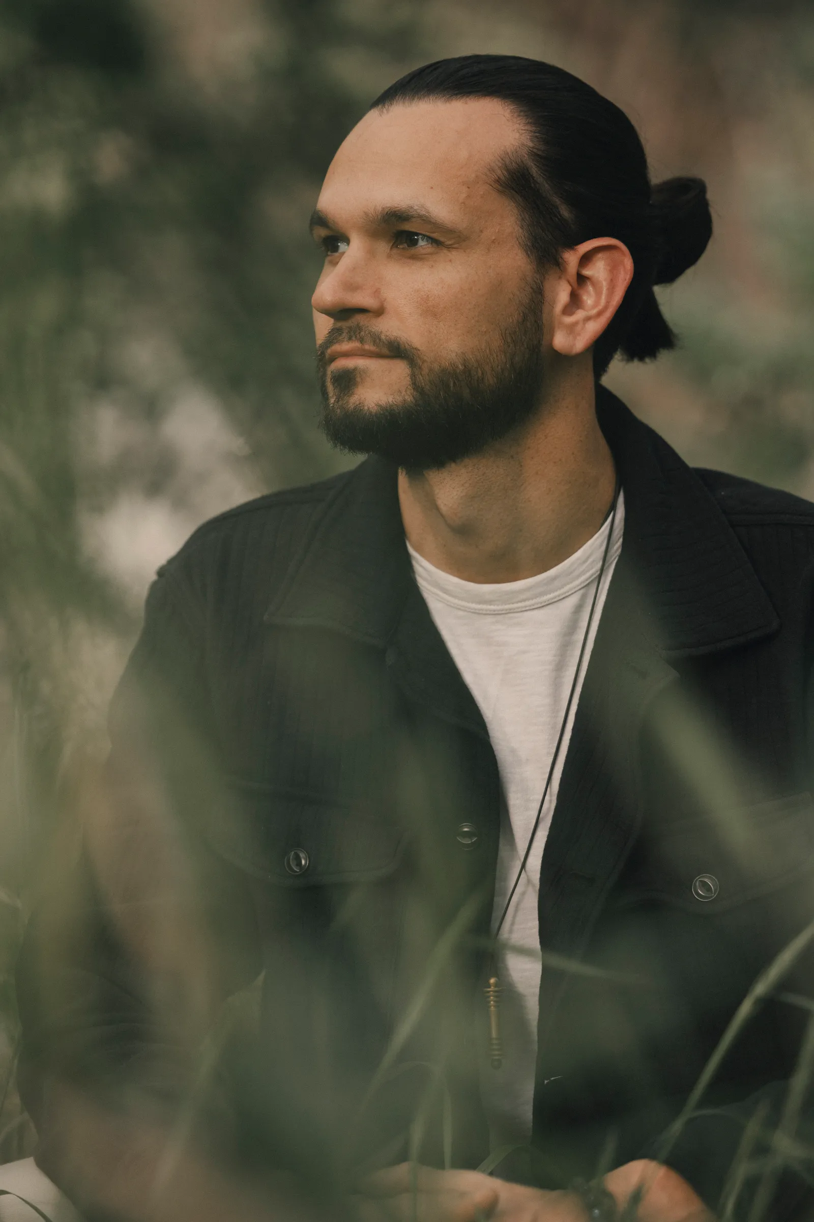 Austin West seated in tall grass, looking away from the camera.