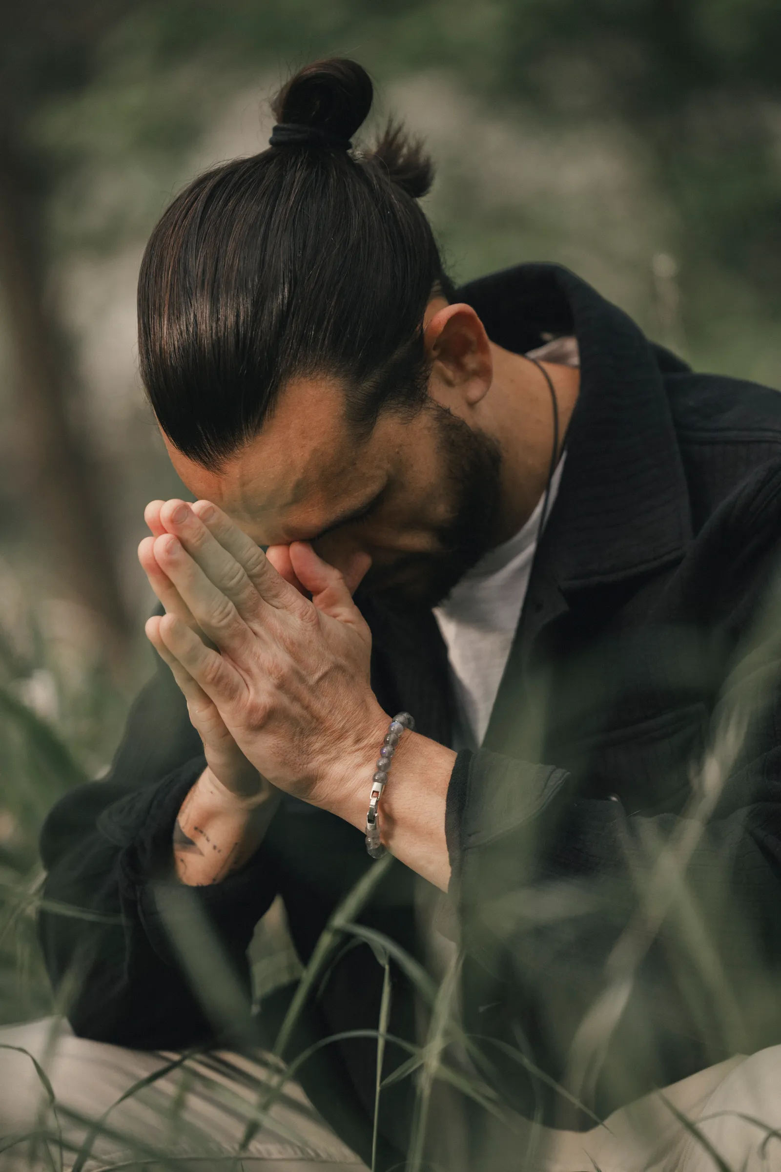 Austin with his head bowed and hands pressed together in prayer
