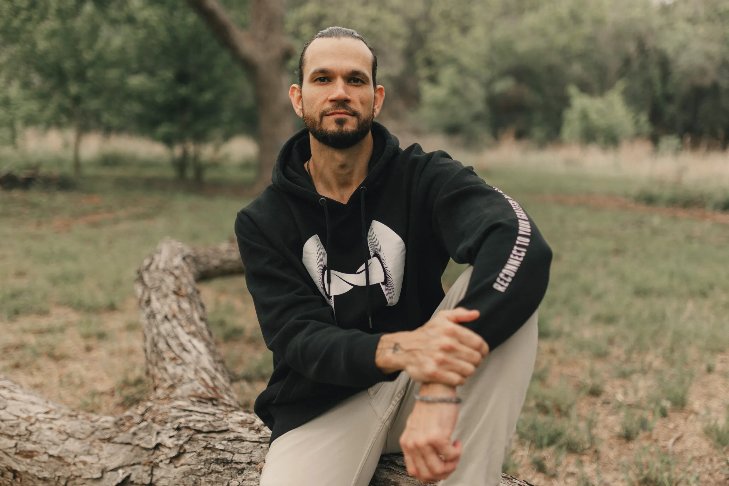 Austin seated on a fallen tree in a field
