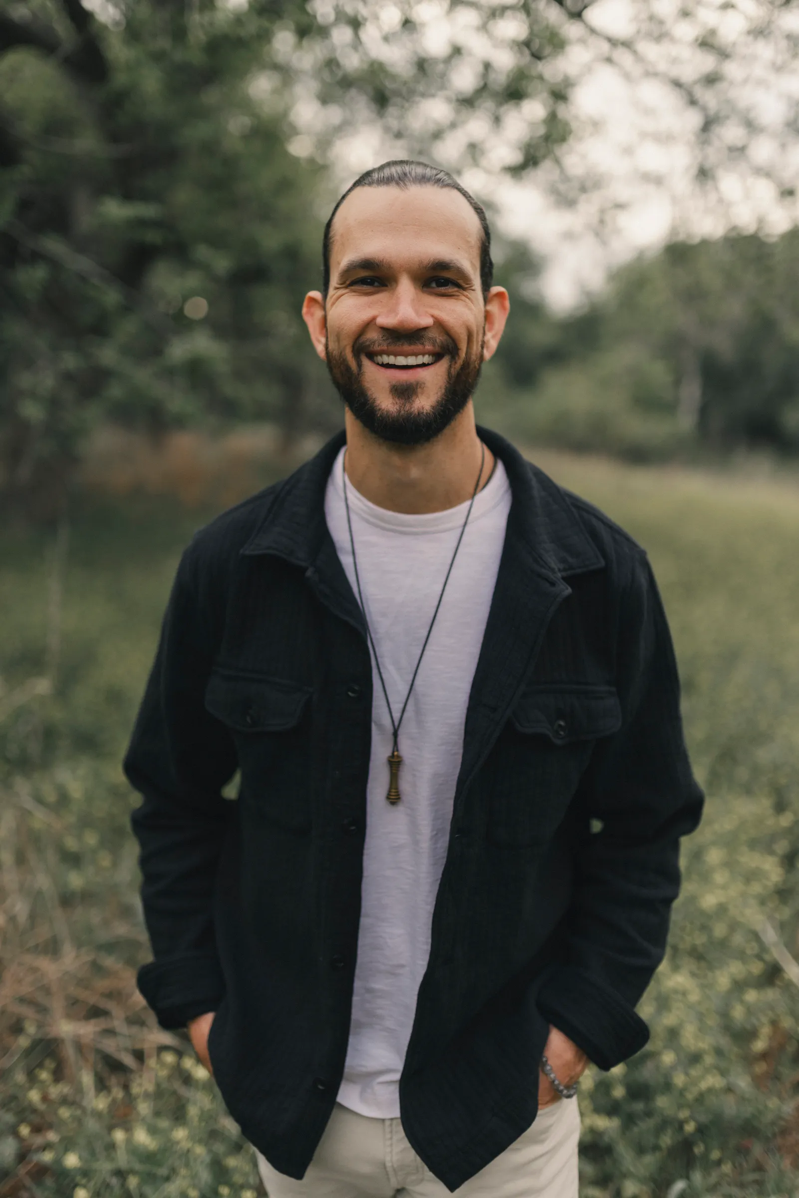 Austin West standing in a field, smiling, hands in his pockets.